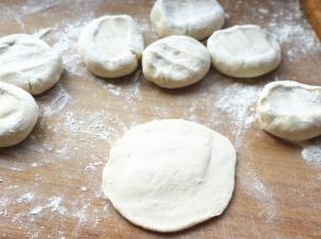 按扁，擀成边缘薄中间厚的面皮。