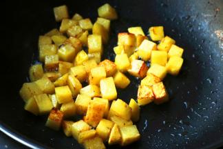 炒锅放油，下入土豆块煎至表面金黄。