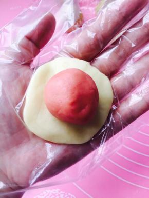 取一油皮按扁，放置一颗粉色油酥