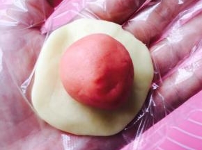 取一油皮按扁，放置一颗粉色油酥