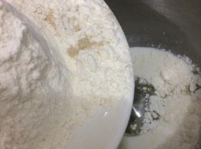 在把面粉、盐和酵母倒入