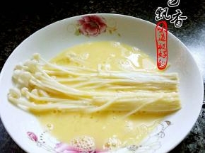 将金针菇放入蛋液，均匀沾上蛋液