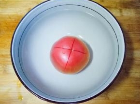 西红柿洗干净，划十字刀，放入碗中，倒入开水烫一会皮，容易去皮