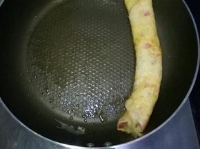 中小火等待鸡蛋液表面半凝固时，用筷子和铲子配合从右往左卷起来推到一边