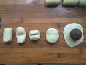 醒发好的油酥皮，对折压扁，擀成圆形，放入豆沙蛋黄