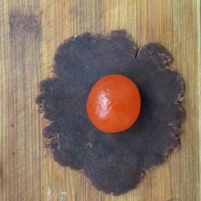 取一豆沙馅按扁包入蛋黄收口搓圆