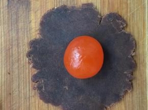 取一豆沙馅按扁包入蛋黄收口搓圆