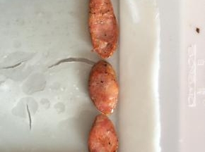 蒸熟的肠粉，用刮板从一头轻轻铲起来，放入香肠片。
