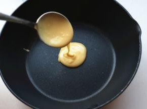 用一个勺子舀一勺面糊，从一个点上倒入锅内，让面糊自然摊开，成一个圆饼。