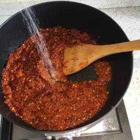 辣椒颜色变深后，倒入适量盐