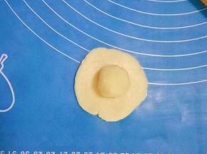 取一个油皮按扁擀成圆皮，放入一个油酥，收口