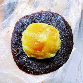 取一个称好的豆沙按扁，放入一个熟蛋黄