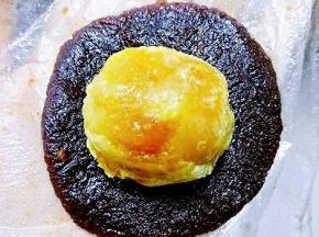 取一个称好的豆沙按扁，放入一个熟蛋黄