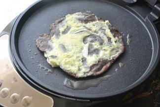 电饼铛少许油将杂粮饼胚放入、一分钟左右翻面，然后倒入适量的鸡蛋液，合上电饼铛