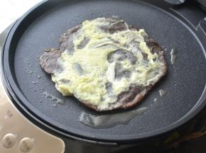 电饼铛少许油将杂粮饼胚放入、一分钟左右翻面，然后倒入适量的鸡蛋液，合上电饼铛