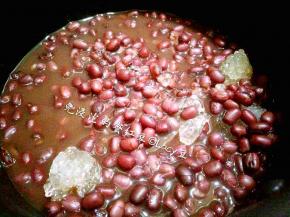 将红豆带汤倒入奶锅中，加入黄冰糖，开中小火，橡胶刮刀搅拌，直到糖化，装碗。