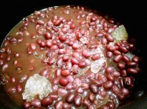 将红豆带汤倒入奶锅中，加入黄冰糖，开中小火，橡胶刮刀搅拌，直到糖化，装碗。