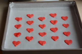 将红色蛋糕糊入裱花袋中，提前在烤盘里再铺一张油纸，在干净的油纸上按照先前画好的心形图案挤上红色的蛋糕糊；这一步动作一定要快，因为时间越长，大盆中的蛋白糊就越容易消泡；然后送入预热好的烤箱中层，烤2分钟定型，然后端出来晾晾