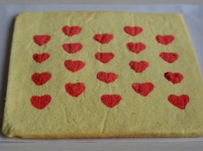 5分钟后，将蛋糕翻面，撕去原来底部的油纸，看，颗颗红心显出来了；将干净的油纸覆盖在表面