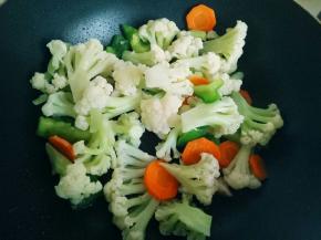 炒出香味后，加入花菜和配菜，翻炒均匀。