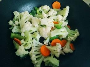 炒出香味后，加入花菜和配菜，翻炒均匀。