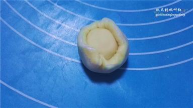 开始包酥：取一份水油皮摁扁，放上油酥；.收口包好；