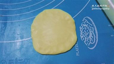 取一份静置好的面团，轻轻摁压下后擀开成中间厚边缘薄的面片；