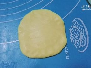 取一份静置好的面团，轻轻摁压下后擀开成中间厚边缘薄的面片；