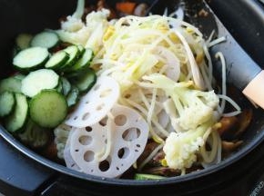 加入上面煮好的蔬菜，以及黄瓜片，继续翻炒。