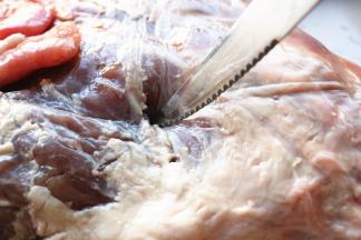 用刀子在羊腿上扎洞，抹上盐腌制24小时以上入味。