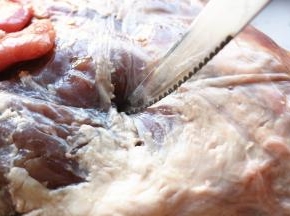 用刀子在羊腿上扎洞，抹上盐腌制24小时以上入味。