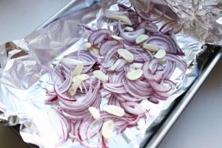 烤盘铺上锡纸，洋葱切丝，蒜切片铺在锡纸上。