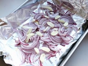 烤盘铺上锡纸，洋葱切丝，蒜切片铺在锡纸上。