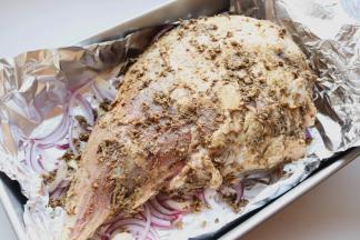 刚才混合好的调料均匀抹在腌过的羊腿上，全身都抹匀，放在烤盘内洋葱上面。