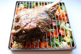 再放烤架在烤盘里蔬菜上面，羊腿刷上刚才的调料，放在烤架上面。