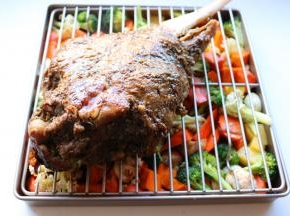 再放烤架在烤盘里蔬菜上面，羊腿刷上刚才的调料，放在烤架上面。