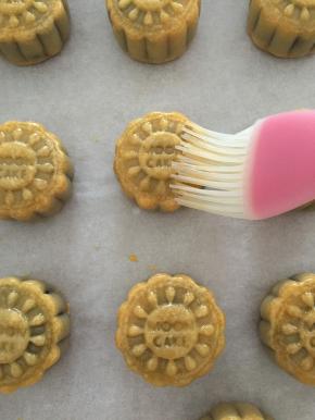 取出烤了10分钟的月饼坯，完全冷却后将鸡蛋打散，用硅胶刷刷一层蛋液在月饼表面；