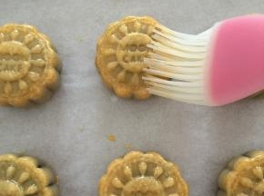 取出烤了10分钟的月饼坯，完全冷却后将鸡蛋打散，用硅胶刷刷一层蛋液在月饼表面；