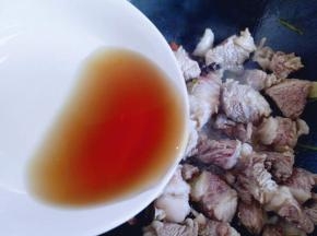 炒出香味时加入肉煸炒，炒至发白，加入料酒。