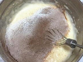 筛入低筋面粉和可可粉的混合物，用刮刀小心地从底部往上翻拌，使蛋糊和面粉混合均匀，不要画圈搅拌，以免消泡