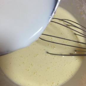 将1/3的牛奶慢慢倒入蛋黄糊里，边倒边搅拌均匀