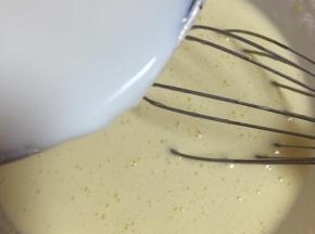 将1/3的牛奶慢慢倒入蛋黄糊里，边倒边搅拌均匀