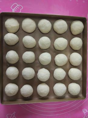 取出面团排气，分割成25克每个的小剂子，揉成圆形，摆在28*28的烤盘上，盖上湿布二次发酵40分钟。