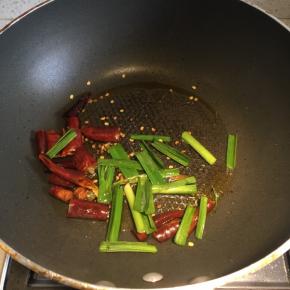 另起炒菜锅，倒入一点点油，先下干辣椒和蒜苗爆香