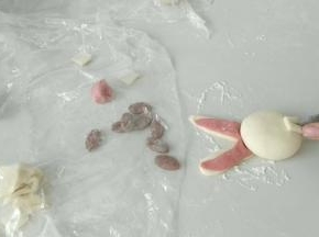 如图这样，做出耳朵，黑色面团整成椭圆形。然后切一块面团做门牙。