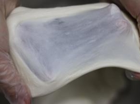 面团吸收橄榄油后，换2档继续和面，揉至面团拉出薄而坚韧的面膜，结束揉面。