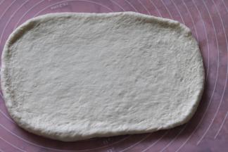 再次擀开，擀成长约20厘米的正方形。从一边往内三分之一出卷起压紧结合处。