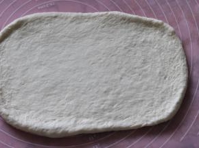 再次擀开，擀成长约20厘米的正方形。从一边往内三分之一出卷起压紧结合处。