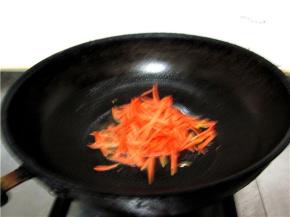 锅中油热后放入葱、姜爆香，然后将胡萝卜丝放入翻炒