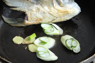 煎鱼的同时放入姜片和葱段一起煎。